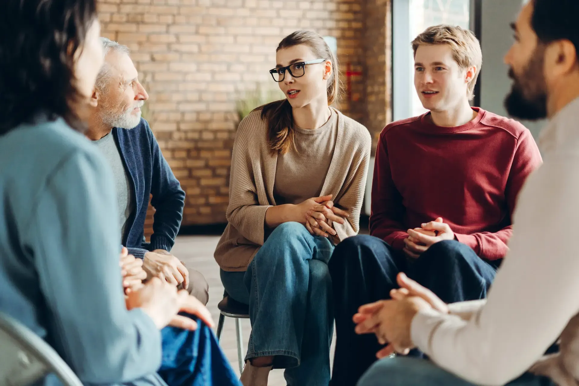 A diverse group of people talking together in a supportive circle